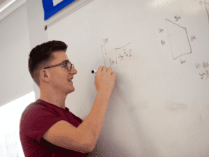 Student writing maths on whiteboard.
