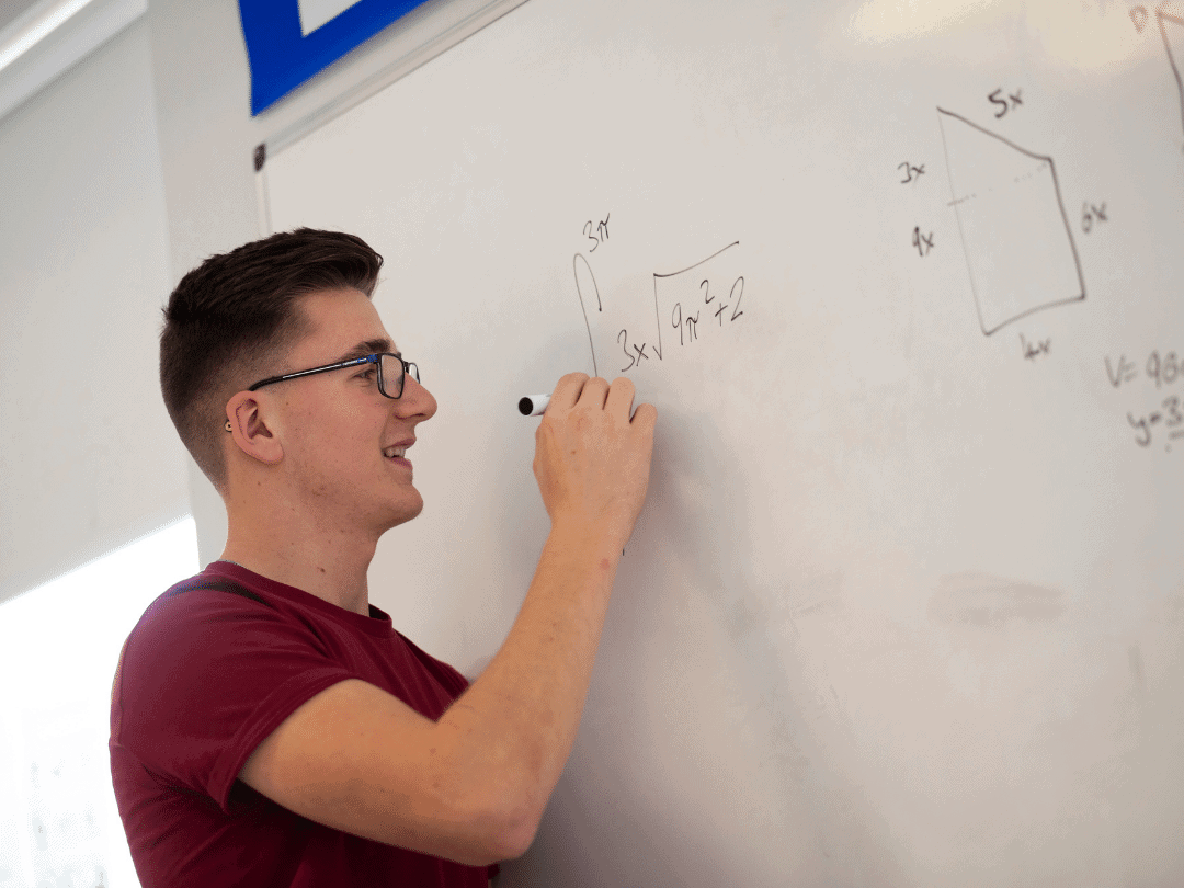 Student writing maths on whiteboard.