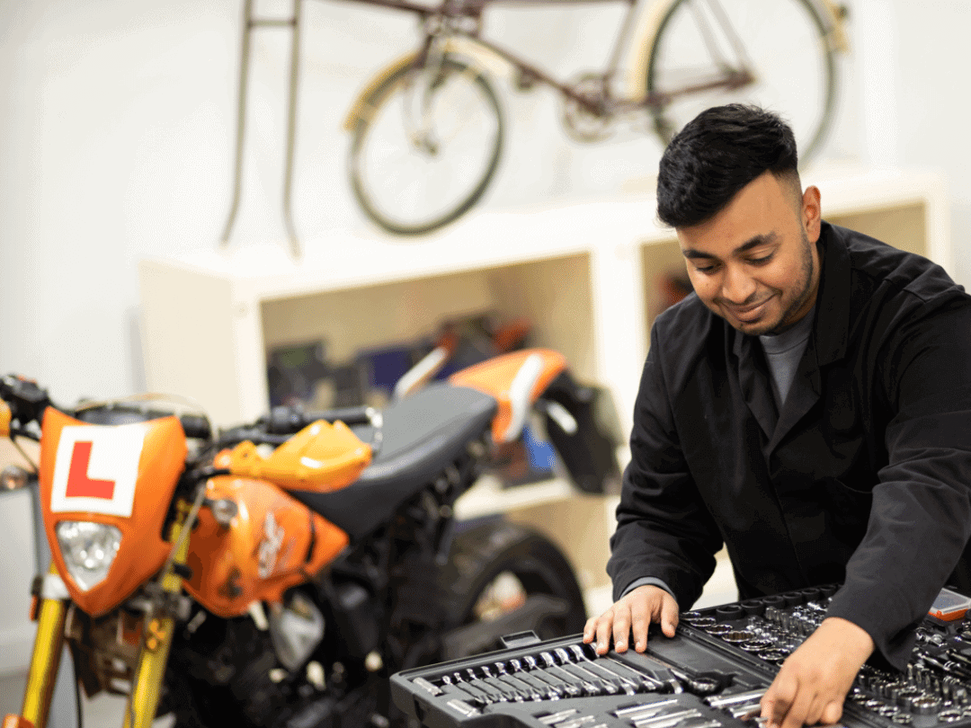 Learner using tools to fix motorbike.