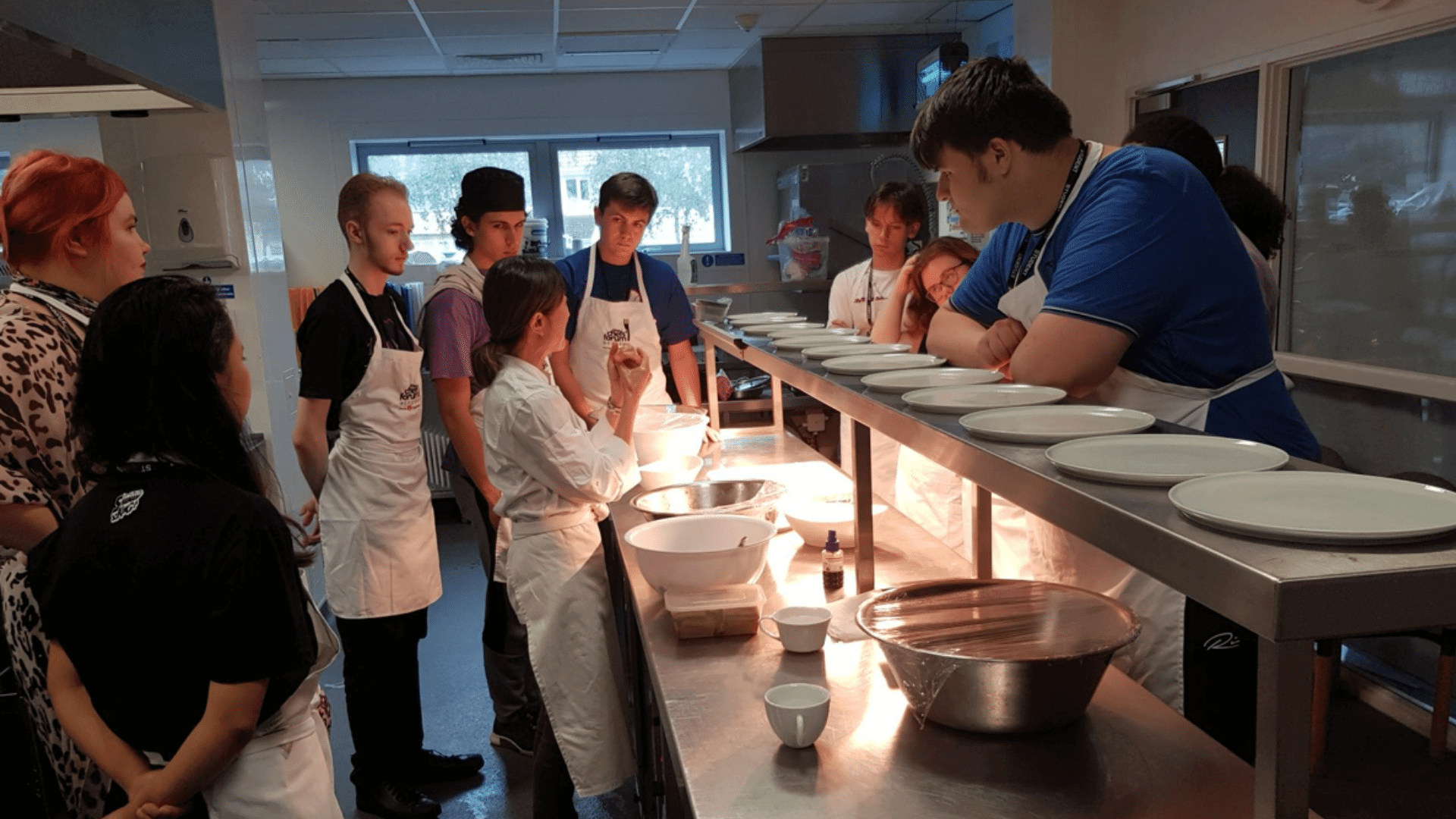 Students in the kitchen watching a demonstration.