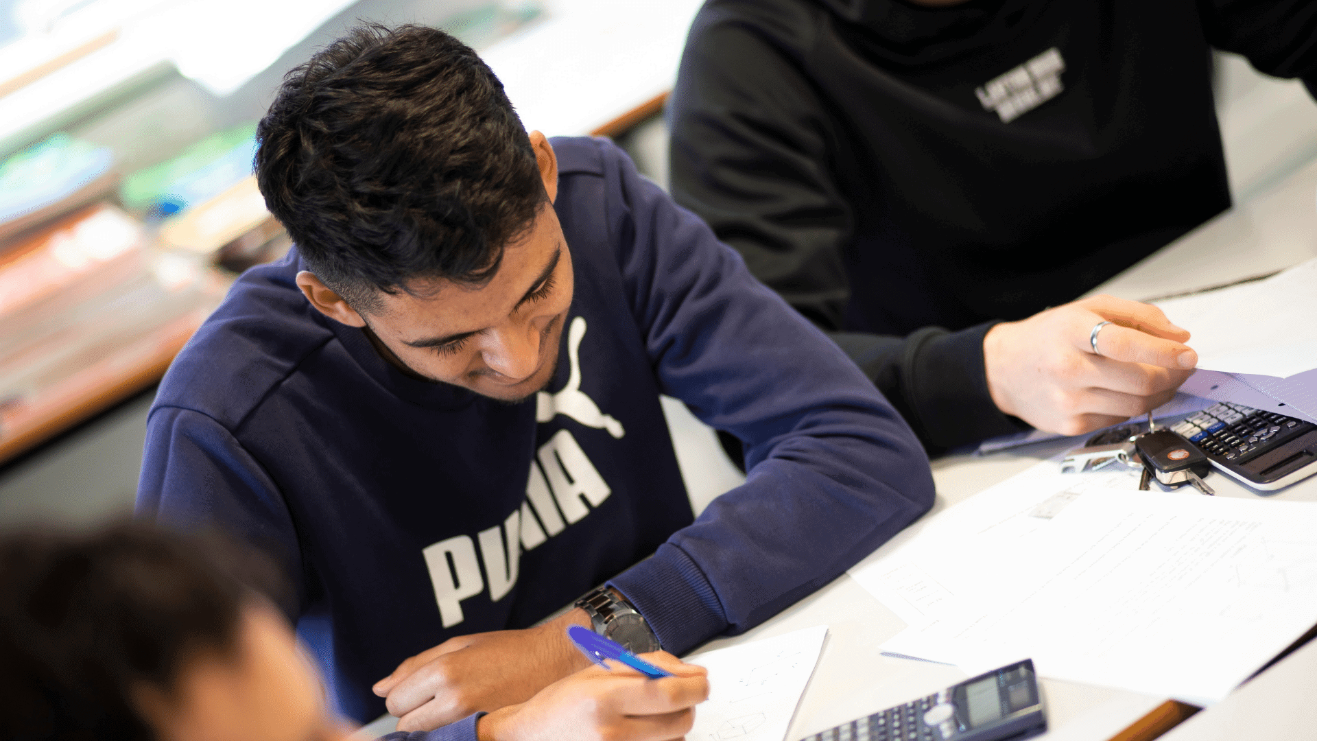 Student at desk with calculator.