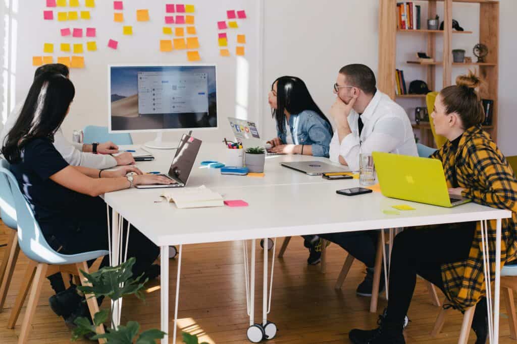 Four adults meeting to discuss their course feedback at a table.