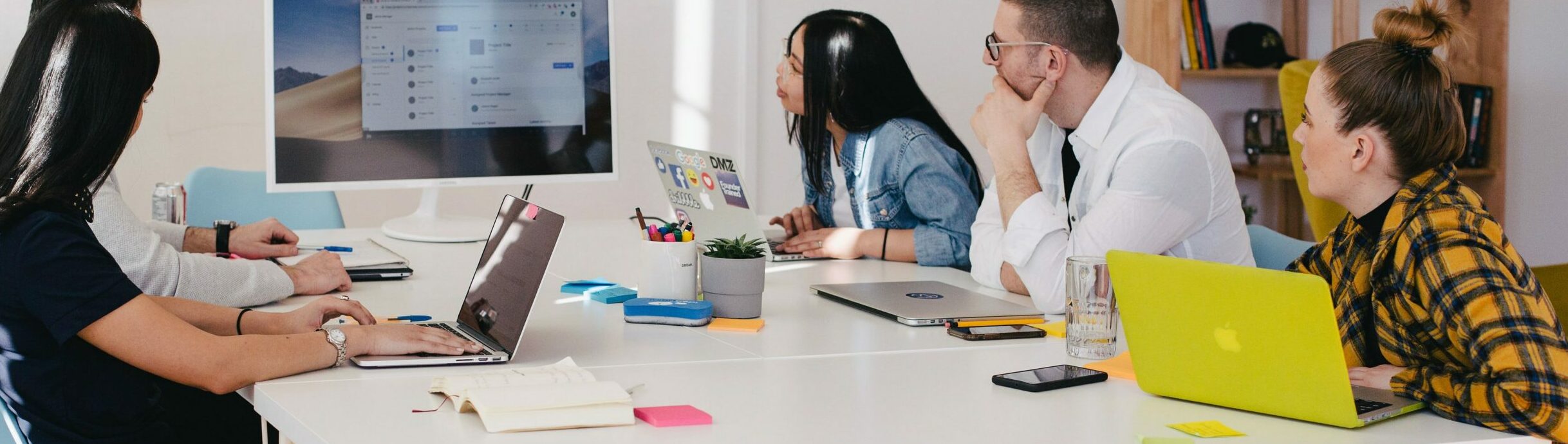 Four adults meeting to discuss their course feedback at a table.