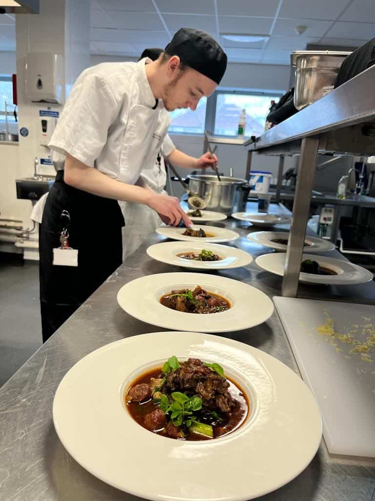 hospitality and catering student plating up a meal