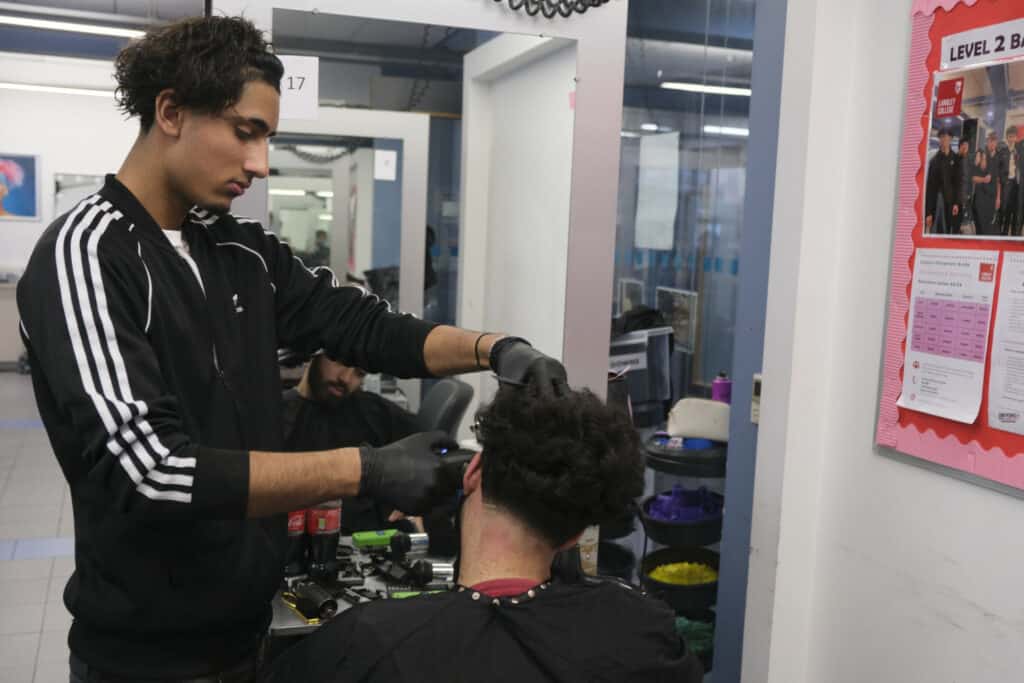 barbering student cuts male hair