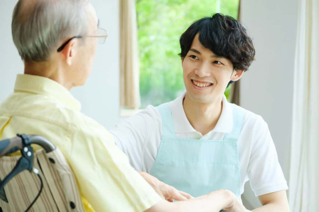 Young person sat smiling at an elderly man in a wheelchair