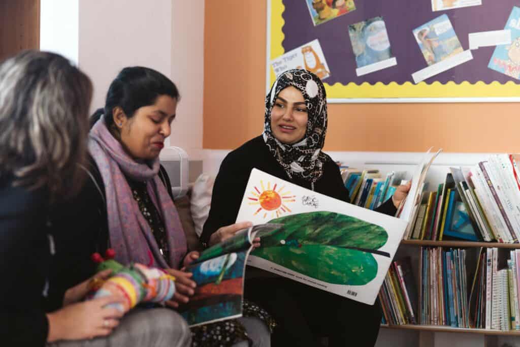 A lady smiling whilst reading The Hungry Caterpillar book