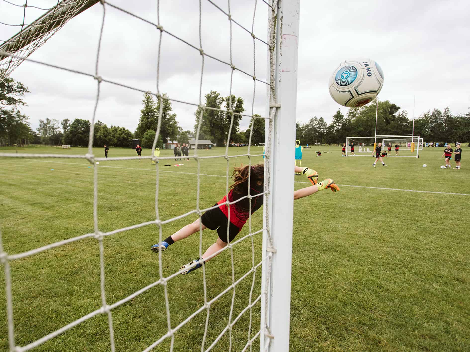 A photo next to a football goal, with the football heading towards the camera