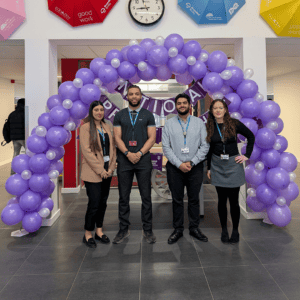 The Apprenticeships team standing in front of a purple balloon arch