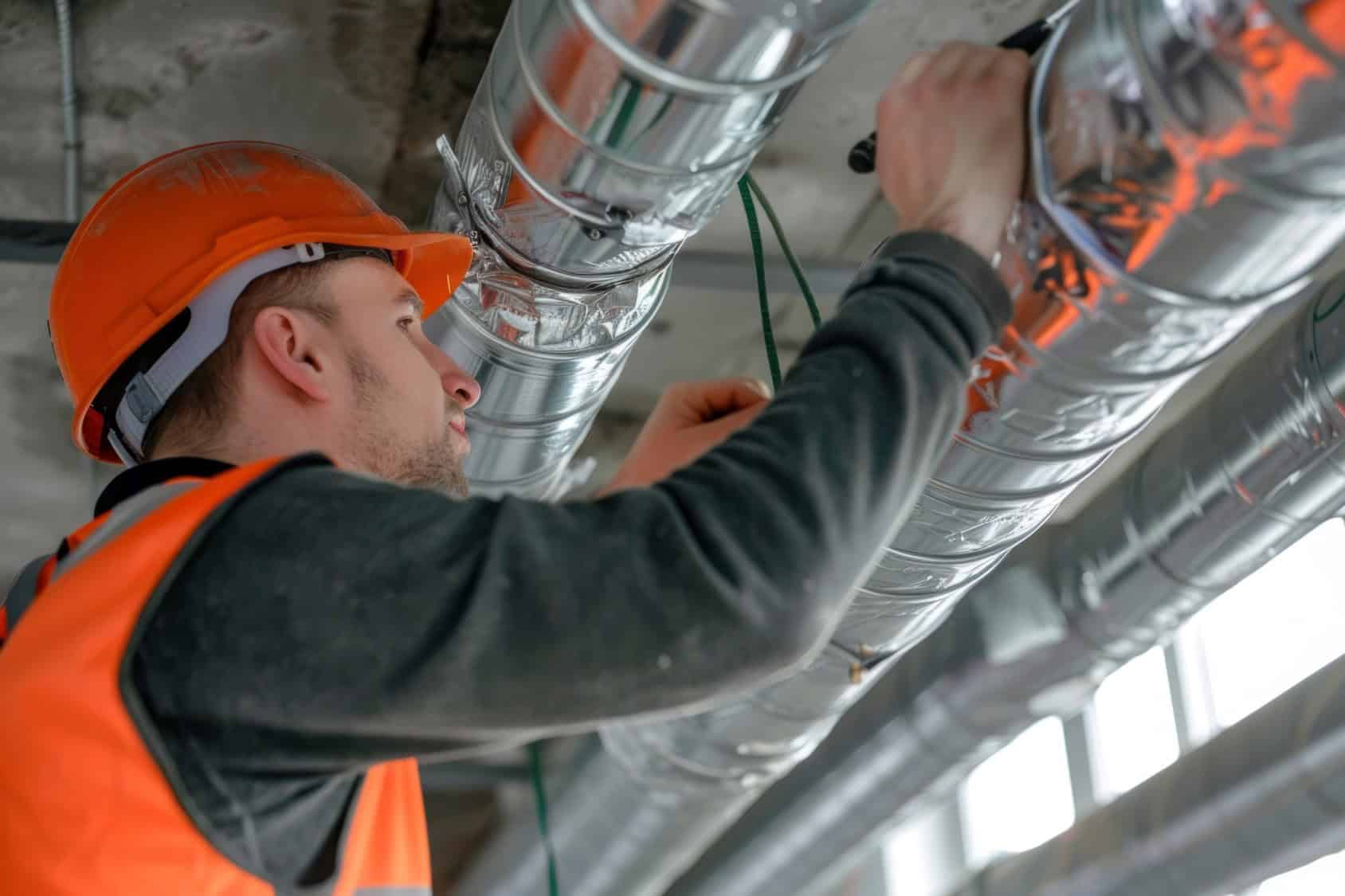 A man looking at metal pipes on the ceiling