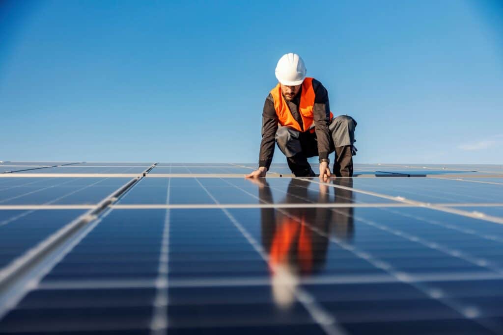A man in high vis fixing solar panels onto the roof