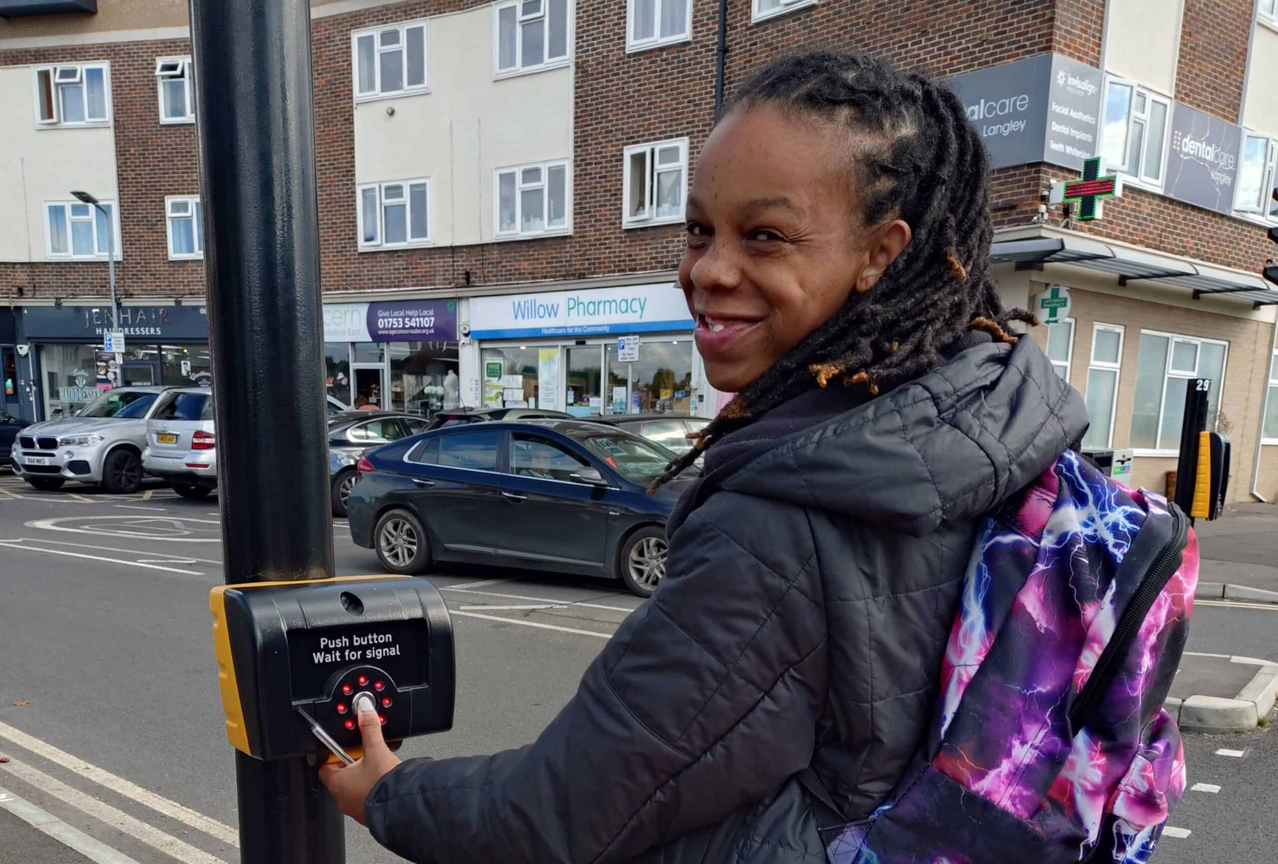 An ALFIE student smiling to the camera whilst waiting at a pedestrian crossing