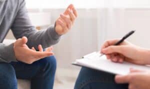 A close up shot of someone writing on paper, and another person's hands whilst talking