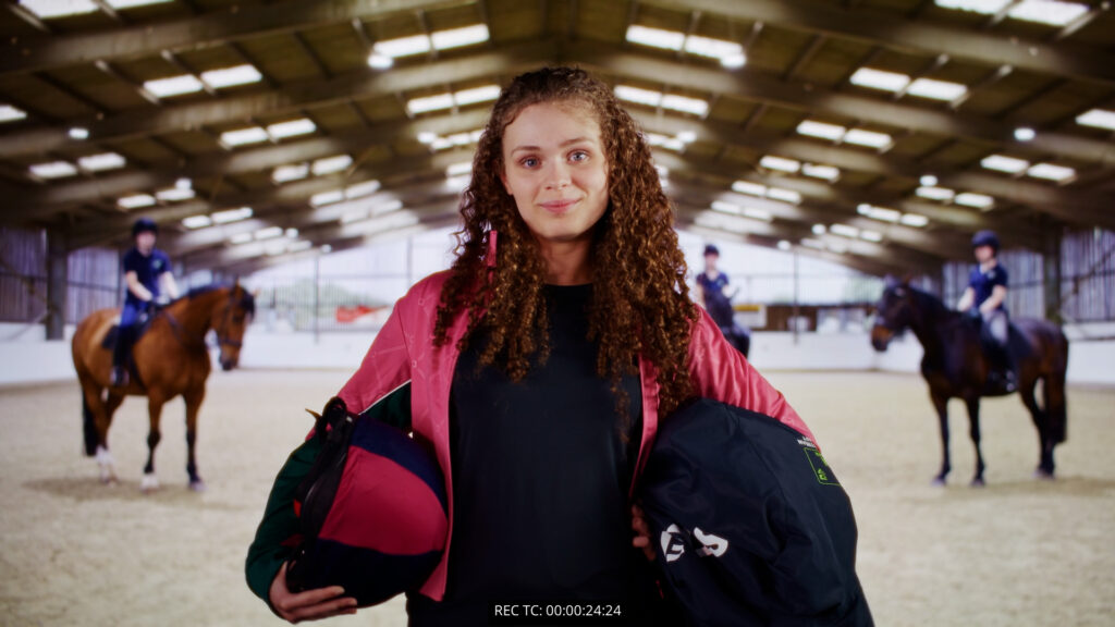 The final scene of our TV advert, featuring a student holding horse riding equipment