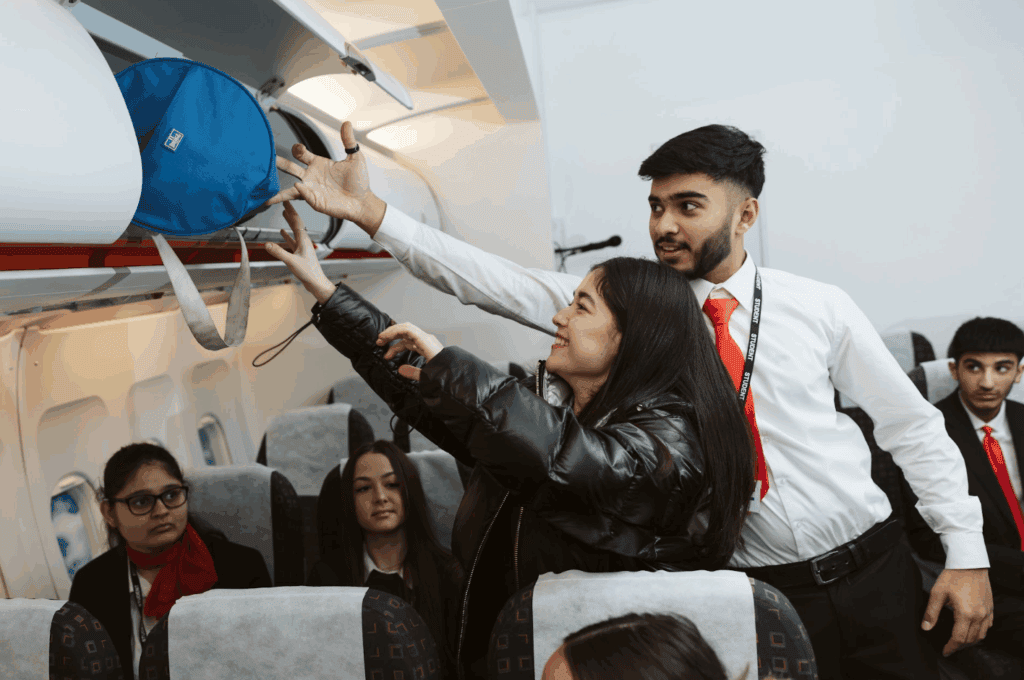 travel and tourism student in the cabin helping a student put her bags in the aeorplane