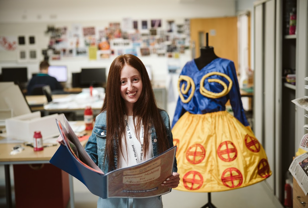student holding a book in front of the mannequin
