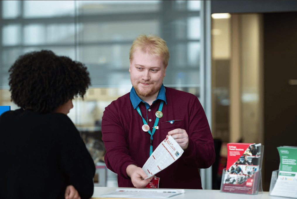 admissions team member talking to a student with a leaflet