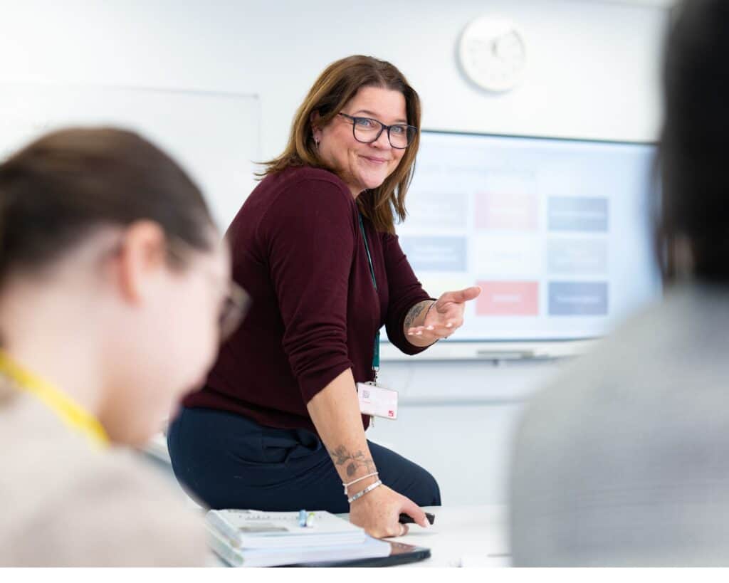 teacher leaning on desk and smiling