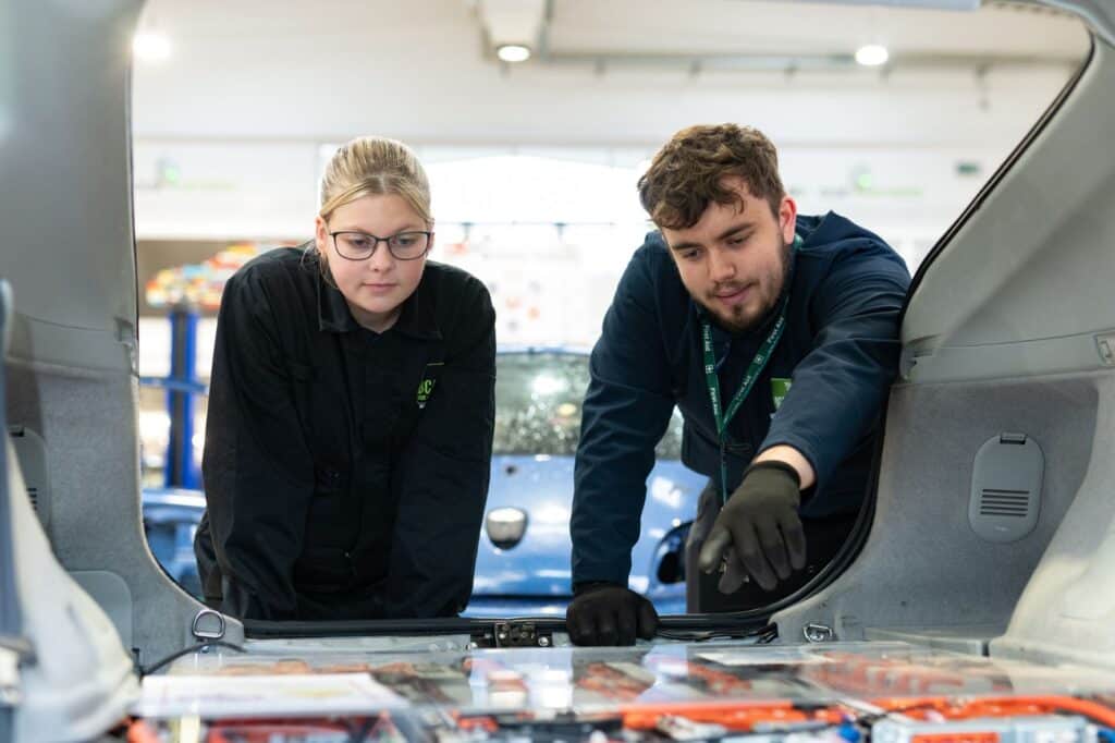 Teacher and female student working on a car