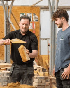 Teacher teaching student how to do brickwork
