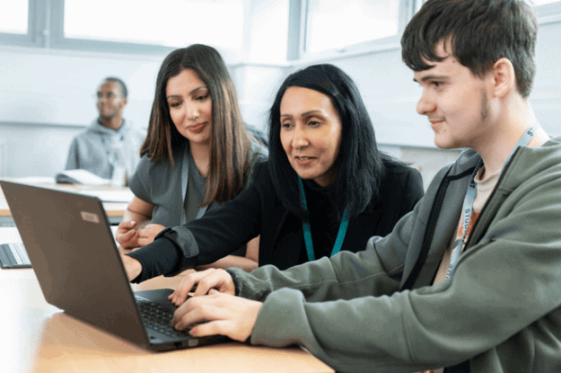 teacher and two students looking at a computer