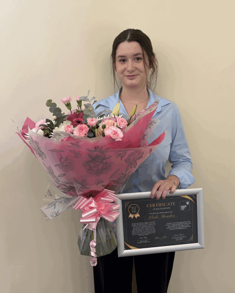 Elodie holding her certificate and some flowers, smiling to the camera