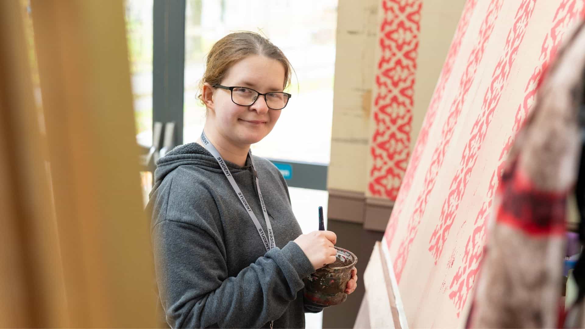 Poppy smiling to the camera, whilst painting a prop