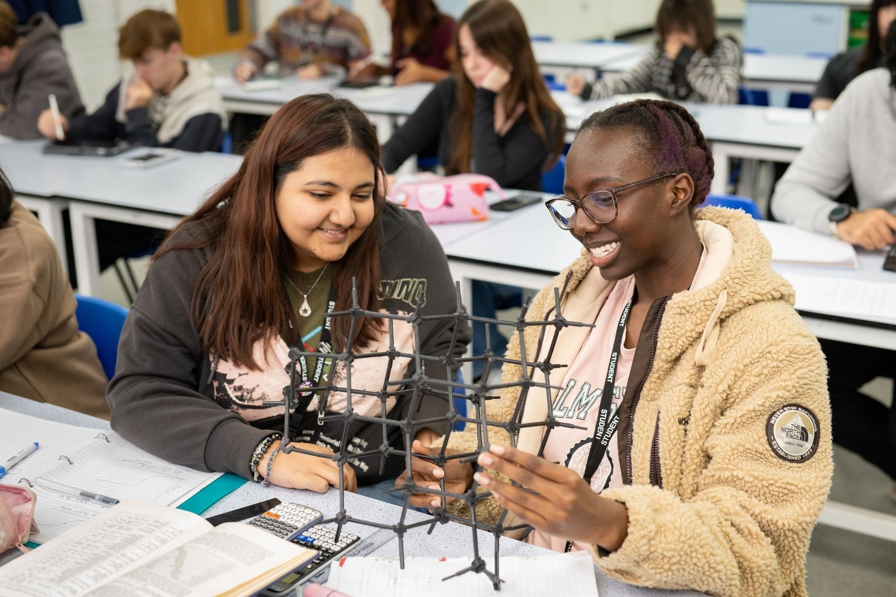 2 students in a science lab with a molecul model