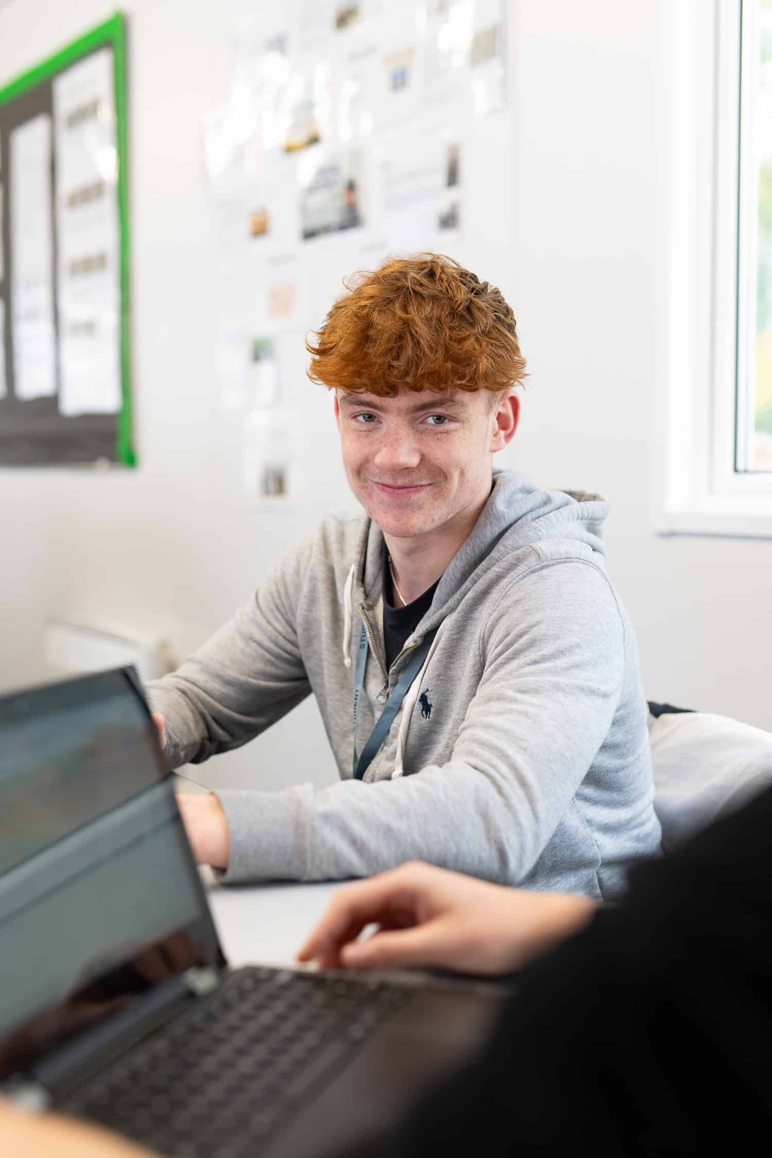 Young man looking up from computer smiling