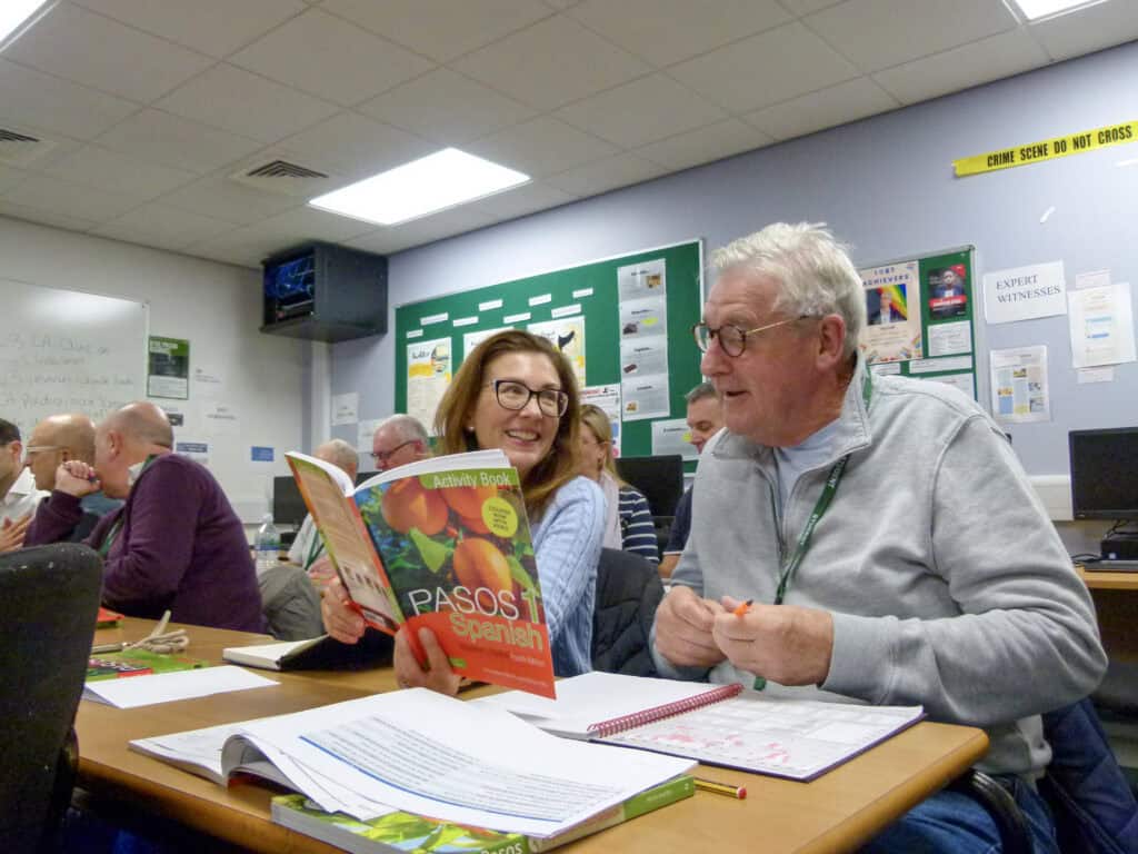 Two adult learners wiht a spanish book
