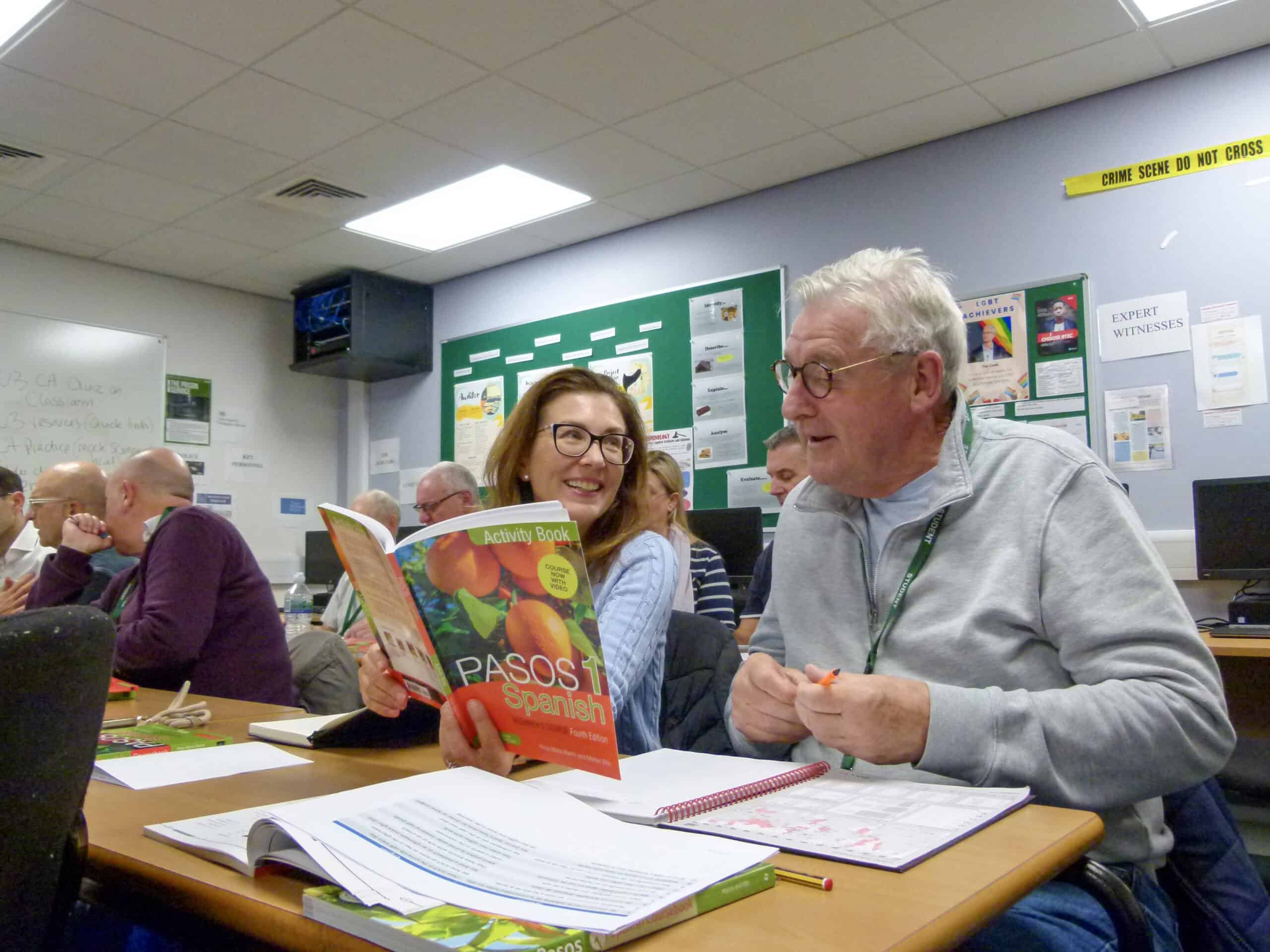 Two adult learners wiht a spanish book