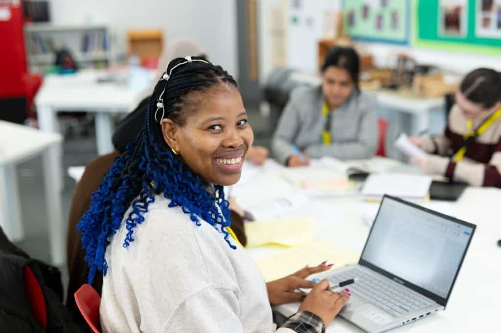 Adilt with blue hair smiling at camera