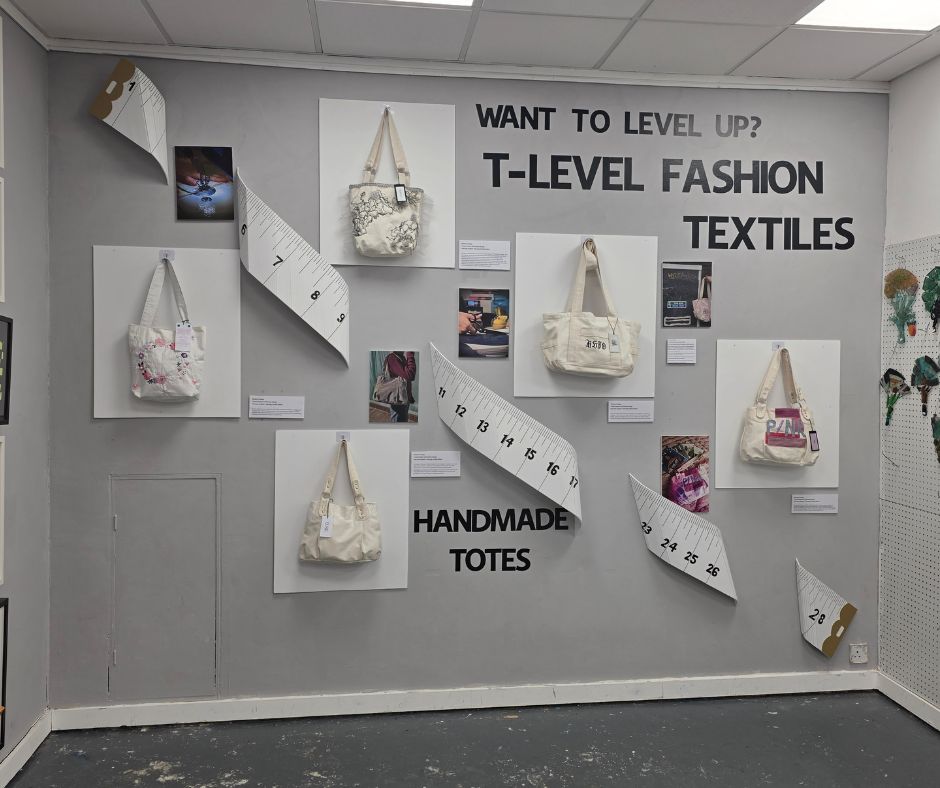 A grey wall with tote bags hanging around the display that the students created