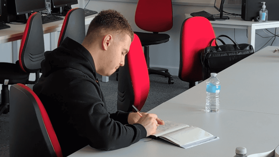 A male learner writing in a notebook