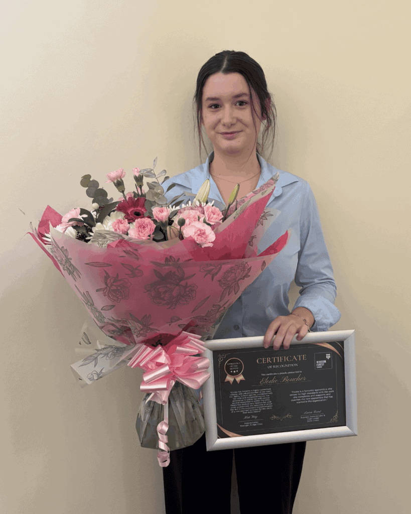 Elodie holding her certificate and some flowers, smiling to the camera